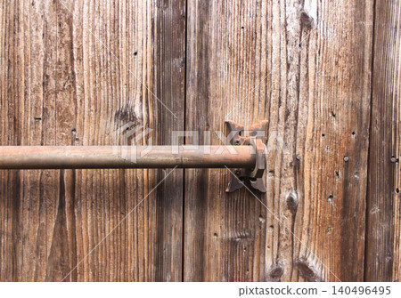 A weathered wooden building with wooden doors and rusty old iron lock fittings. Retro architectural details. 140496495