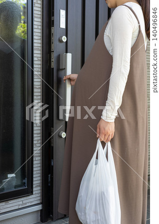 A pregnant woman in her final month of pregnancy is about to open the door to her home after returning from shopping. A pregnant woman in her final month of pregnancy is about to open the door to her home after returning from shopping. 140496846