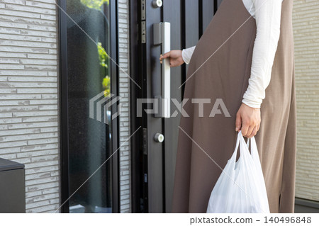 一位懷孕最後一個月的孕婦購物回來後，正準備打開家門。 140496848