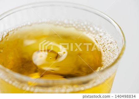 Cold, amber-colored tea poured into a glass filled with ice. Cold, amber-colored tea poured into a glass filled with ice. 140498834