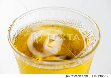 冰涼的琥珀色茶水倒入裝滿冰塊的玻璃杯中。 冰涼的琥珀色茶水倒入裝滿冰塊的玻璃杯中。 140498837