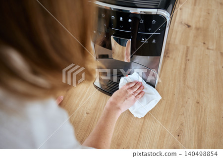 Person cleaning coffee machine with cloth on kitchen counter Person cleaning coffee machine with cloth on kitchen counter 140498854