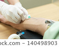 The hands of a healthcare worker administering a vaccination to a patient's arm in a medical setting. 140498903