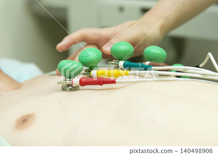 準備進行心電圖 (ECG) 檢查的場景，病人手持電極導線進行醫學檢查。 140498906