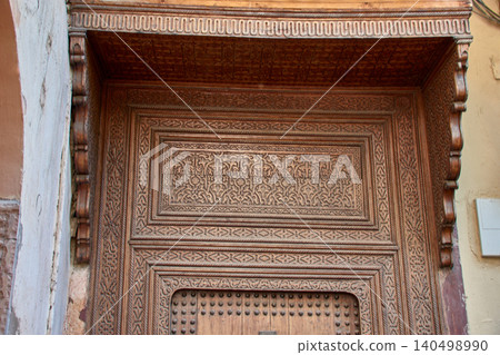 The intricate cedar door with traditional engravings decorates an old facade in the city of Fez. 140498990