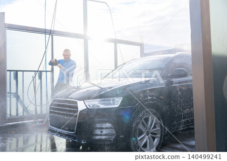 Man Washing Car at Self Service Car Wash Using high pressure Water Cleaning System. Natural daylight highlights the water droplets, foam texture and reflective vehicle surfaces. Concept of vehicle Man Washing Car at Self Service Car Wash Using high pressure Water Cleaning System. Natural daylight highlights the water droplets, foam texture and reflective vehicle surfaces. Concept of vehicle 140499241