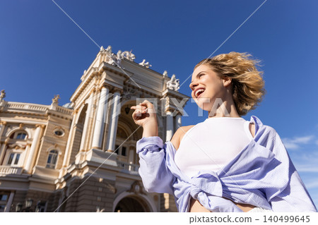 Woman enjoys sunny day standing in front of historic building Woman enjoys sunny day standing in front of historic building 140499645