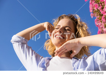 Woman smiles and poses with flowers in the background 140499649