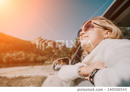 Woman, Car, Road Trip: Happy Woman Enjoying Scenic View from Car Window During Sunset. 140500543