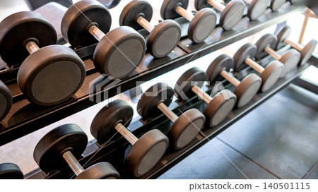 Set of dumbbells lined up by size on metal gym rack Set of dumbbells lined up by size on metal gym rack 140501115