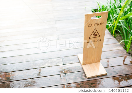 Wet Floor Caution sign with slippery man symbol on wet wood floor after the rain Wet Floor Caution sign with slippery man symbol on wet wood floor after the rain 140501122