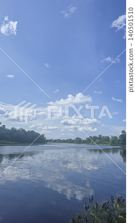 A deep river surrounded by trees and plants Thickets of reeds. Voluminous clouds 140501510
