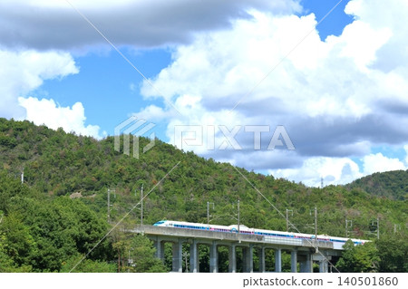 一列裹著外套的新幹線列車行駛在綠色的風景中 140501860