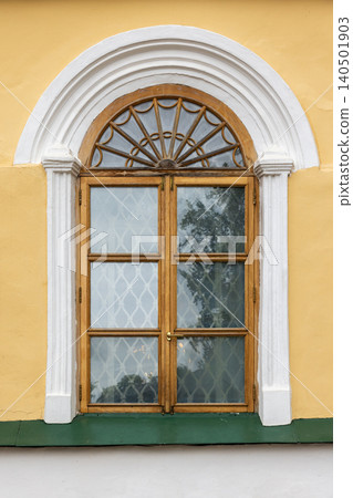 Arched wooden window set in a warm yellow stucco facade Arched wooden window set in a warm yellow stucco facade 140501903