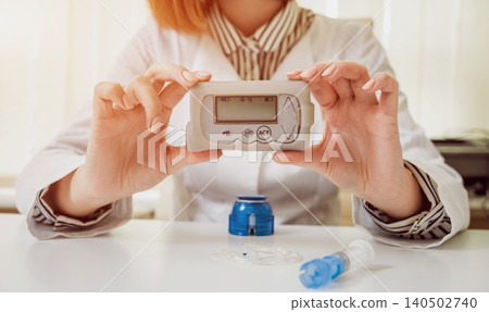 Doctor holding the insulin pump at his hands. 140502740