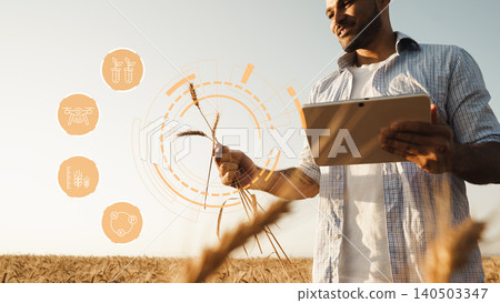 Smart farm technology in use by a farmer holding wheat in a field during daytime Smart farm technology in use by a farmer holding wheat in a field during daytime 140503347