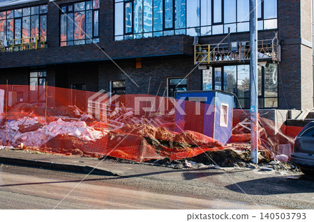 Construction Site Scene Featuring Heavy Machinery, Safety Barriers, and Groundwork in Progress Near an Urban Building Project Construction Site Scene Featuring Heavy Machinery, Safety Barriers, and Groundwork in Progress Near an Urban Building Project 140503793