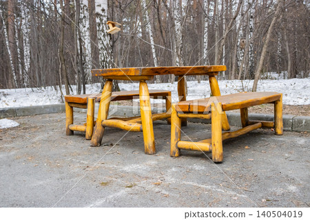 Rustic Wooden Picnic Table Set in a Winter Landscape Surrounded by Bare Trees and Snow Rustic Wooden Picnic Table Set in a Winter Landscape Surrounded by Bare Trees and Snow 140504019