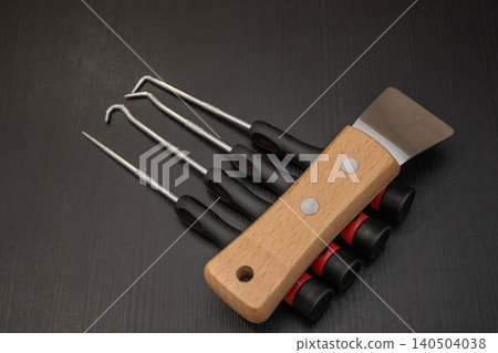 Set of metal pick tools and scraper with wooden handle on black workbench Set of metal pick tools and scraper with wooden handle on black workbench 140504038