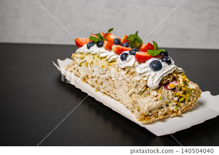 Dessert roulade cake with whipped cream, strawberry, blueberry and mint on dark table with copy space Dessert roulade cake with whipped cream, strawberry, blueberry and mint on dark table with copy space 140504040