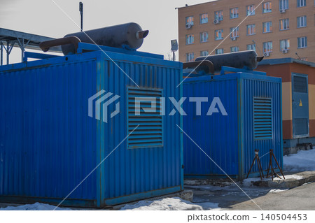 Industrial Blue Shipping Containers with Equipment on Rooftops in an Urban Environment Surrounded by Snow and Brick Buildings Industrial Blue Shipping Containers with Equipment on Rooftops in an Urban Environment Surrounded by Snow and Brick Buildings 140504453