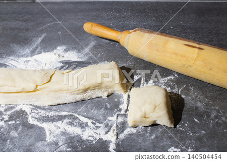 A Culinary Scene Featuring Rolled Dough and Flour Dust on a Kitchen Surface with a Wooden Rolling Pin Ready for Baking Preparation A Culinary Scene Featuring Rolled Dough and Flour Dust on a Kitchen Surface with a Wooden Rolling Pin Ready for Baking Preparation 140504454