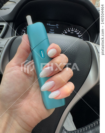 Close-Up of a Stylish Hand Holding a Mint-Colored Device with Beautifully Designed Glittery Nails Captured Inside a Car Interior Close-Up of a Stylish Hand Holding a Mint-Colored Device with Beautifully Designed Glittery Nails Captured Inside a Car Interior 140504464