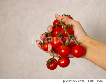 Hand holding vine cherry tomatoes against neutral background with copy space Hand holding vine cherry tomatoes against neutral background with copy space 140504502