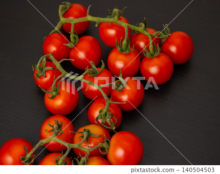 Cherry tomatoes on the vine on dark table surface with copy space Cherry tomatoes on the vine on dark table surface with copy space 140504503