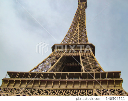 A Captivating View of the Eiffel Tower, Showcasing Its Iconic Iron Structure and Architectural Grandeur from an Upward Perspective Against a Cloudy Sky 140504511