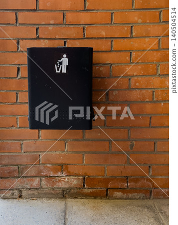 A Modern Trash Bin Attached to a Brick Wall with a Figure Indicating Proper Waste Disposal Guidelines in Urban Spaces 140504514