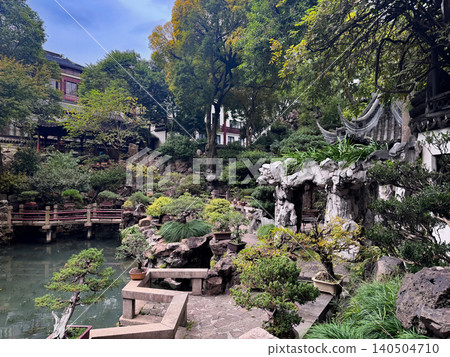 Classical Chinese garden with pond, rockery and bonsai potted plants in traditional courtyard setting Classical Chinese garden with pond, rockery and bonsai potted plants in traditional courtyard setting 140504710