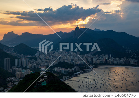 Scenic aerial view of Rio de Janeiro cityscape at sunset with majestic mountains and dramatic cloudy sky over bay Scenic aerial view of Rio de Janeiro cityscape at sunset with majestic mountains and dramatic cloudy sky over bay 140504770