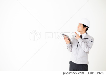 A middle-aged businessman in gray work clothes holding a tablet, against a white background. A middle-aged businessman in gray work clothes holding a tablet, against a white background. 140504928