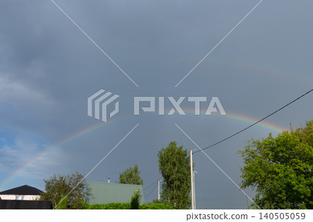 Double rainbow in dark stormy sky after rain. Countryside landscape with green trees Double rainbow in dark stormy sky after rain. Countryside landscape with green trees 140505059