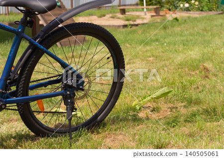 Blue mountain bike parked on green grass in the backyard on a sunny day Blue mountain bike parked on green grass in the backyard on a sunny day 140505061