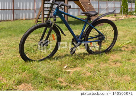 Close-up of a blue mountain bike with muddy fenders on a green lawn outdoors Close-up of a blue mountain bike with muddy fenders on a green lawn outdoors 140505071