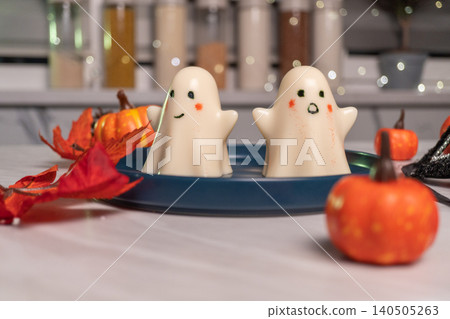 Cute ghost figurines and mini pumpkins on blue plate in autumn kitchen 140505263