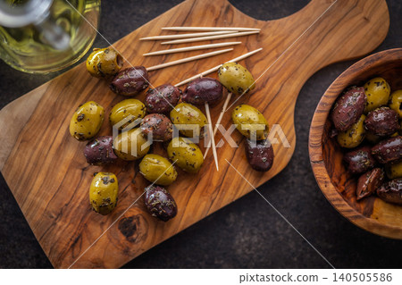 Marinated Olives On Wooden Board With Toothpicks And Olive Oil For Appetizer Platter Marinated Olives On Wooden Board With Toothpicks And Olive Oil For Appetizer Platter 140505586
