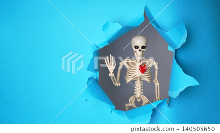 Playful Skeleton with Heart Peeking Through Torn Blue Background in a Whimsical Display Playful Skeleton with Heart Peeking Through Torn Blue Background in a Whimsical Display 140505650