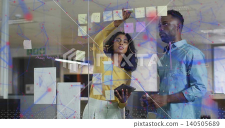 Writing woman in yellow-top holding tablet or marker, man in blue-shirt watching office glass Postit Writing woman in yellow-top holding tablet or marker, man in blue-shirt watching office glass Postit 140505689