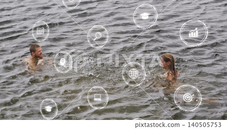 Swimming two adults wearing swimsuits making splashes in dark lake water with white icons 140505753