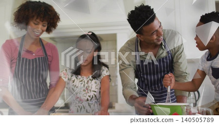 Gathering family of four rolling and whisking dough at home kitchen island, wearing striped aprons 140505789