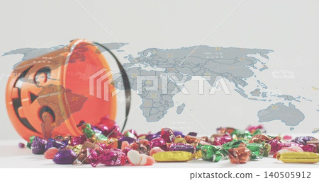 Tipping orange jack-o-lantern bucket, spilling colorful candies across white table, faint world map Tipping orange jack-o-lantern bucket, spilling colorful candies across white table, faint world map 140505912