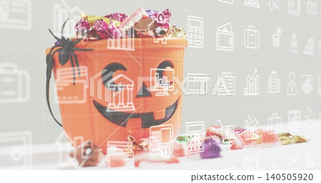Displaying orange jackolantern bucket holding wrapped candies, spider on white table, finance icons Displaying orange jackolantern bucket holding wrapped candies, spider on white table, finance icons 140505920