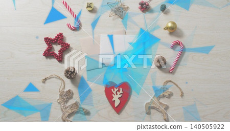 Resting red heart reindeer-cutout ornament on pale envelope on wood tabletop, showing blue overlays Resting red heart reindeer-cutout ornament on pale envelope on wood tabletop, showing blue overlays 140505922