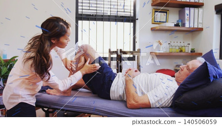 Leaning clinician mobilizing patient's knee on exam table in clinic, wearing blouse, blue pillow Leaning clinician mobilizing patient's knee on exam table in clinic, wearing blouse, blue pillow 140506059