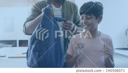 Adjusting father holding navy backpack at kitchen counter, child raising hands in pink T-shirt Adjusting father holding navy backpack at kitchen counter, child raising hands in pink T-shirt 140506071