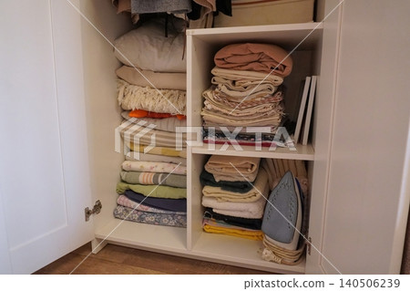 Organized Storage Solutions: Neatly Arranged Linens and Fabric Essentials in a Closet Organized Storage Solutions: Neatly Arranged Linens and Fabric Essentials in a Closet 140506239