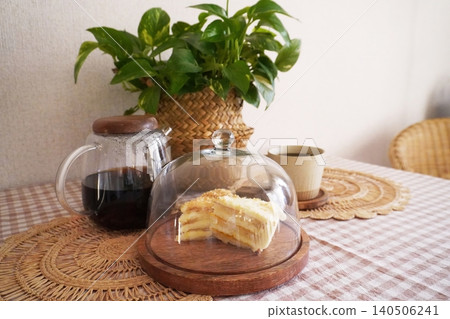 Delicious Layered Cake Under Glass Dome with Coffee and Potted Plant on Rustic Table Setting Delicious Layered Cake Under Glass Dome with Coffee and Potted Plant on Rustic Table Setting 140506241